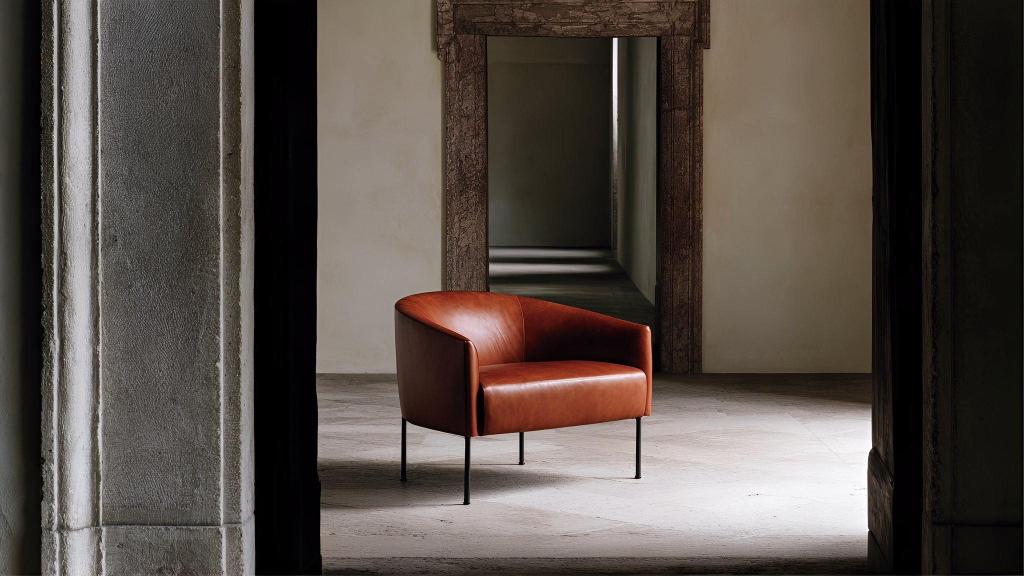 A saddle-brown leather armchair framed by historic stone doorways and a deep corridor